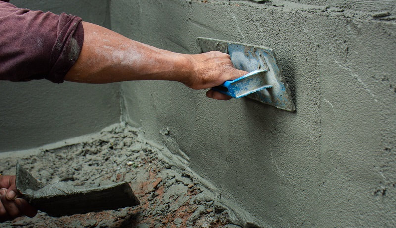 Concrete contractor using a tool to smooth out wet concrete during a repair